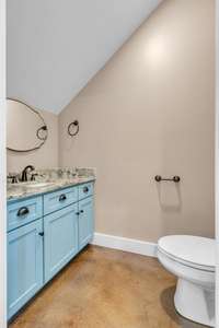 A stylish powder bath on the main level, featuring striking blue cabinetry and luxurious granite countertops.