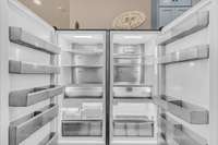 The kitchen features an industrial-sized fridge and freezer, perfect for large gatherings or serious meal prep. Equipped with interior water dispenser. The design blends rustic charm with modern efficiency.
