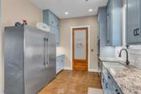 Sleek stained concrete floors that add warmth and character. The space boasts a very large walk-in pantry with a convenient pocket door. Rustic yet modern, the kitchen blends practical design with stylish, durable finishes.