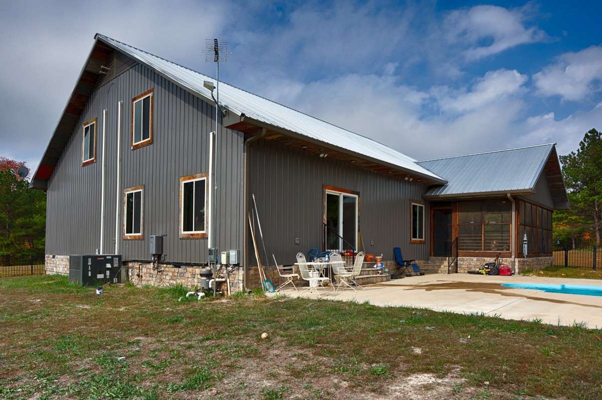 Back of house- metal siding and roof, screened porch, rock foundation and trim
