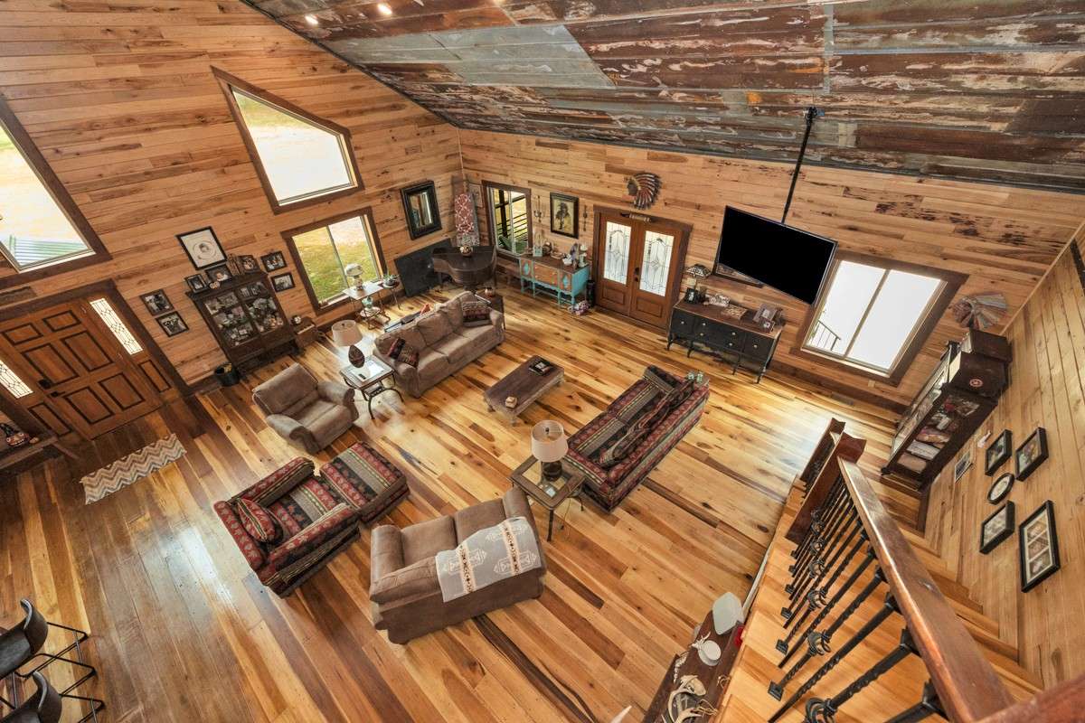 View of living room form top of stairs - Poplar flooring, hickory walls, vaulted metal ceiling, large windows