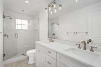 Beautifully updated bathroom featuring a frameless glass walk-in shower, double vanity with quartz countertops, elegant hardware, and designer lighting—delivering both style and function in a bright, spa-inspired space.