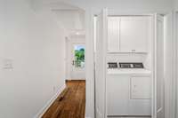 Conveniently tucked away, this bright laundry area features upper cabinet storage, modern appliances, and easy access to the outdoors—combining practicality with clean, efficient design.