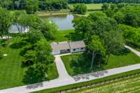 Renovated 2,055 sq ft secondary farmhouse with 3 beds, 2 baths, 1-car garage, and outdoor parking pavilion—strategically positioned at the front of the property beneath towering trees to capture stunning lake and property views.