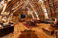 Barn door windows invite refreshing air drafts as light dances off the roof. This loft speakeasy exudes Prohibition-era charm with a custom bar, Sonos system, industrial fans, and curated vintage touches. Currently unfurnished.