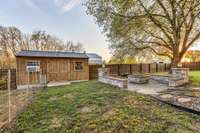 Fire pit with stone/rock/brick seating and the outbuilding with heat/air and dog ramp.