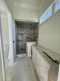 Main Level Guest Suite with en- suite bath featuring a curbless walk- in shower and double vanities.