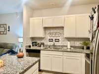 Beautiful kitchen with white cabinets with granite countertops and tile backsplash; Large island for additional workspace or eat a fast bite in the morning;