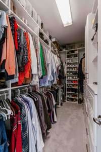 Extra large, primary walk-in closet with wood shelving, drawers, and shoe rack.