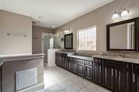 Primary bathroom has separate vanities, air jet bathtub, and separate tiled shower.