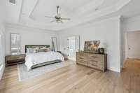 Main Level Primary Ensuite with Tiered Vaulted Ceiling, Ceiling Fan & Door to Screed-In Deck