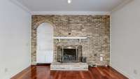Den area shown with hardwood floors, a fireplace, and an enclosed shelf.