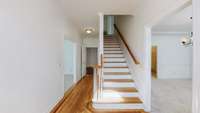 Hardwood flooring extends through the foyer and into the den entrance.