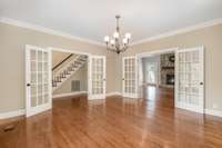 This formal living room offers endless possibilities. Framed by elegant double French doors, the space can easily serve as a home office, music room, library, or traditional sitting room. Natural light pours in, creating a warm & welcoming atmosphere
