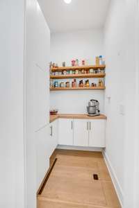 A spacious walk-in pantry just off the kitchen, featuring custom shelving and smart storage—designed to keep daily essentials beautifully organized and easily within reach.