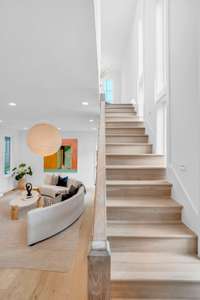 The stairway off the living room offers a quiet transition to the home’s upper level, maintaining the same warmth and design-forward feel throughout.