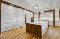 Huge center island with undermount prep sink, electrical outlets and storage below. SubZero refrigerator, freezer, and glass-front wine tower refrigerator.