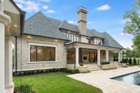 A view of the back of the home with its custom chimney caps, outdoor covered porch and fireplace.