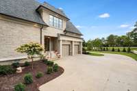This home features a total of 4 Garages. Two bays on either side of the home. Here is a view of one of the garage and the friends entry on the north side of the home. Also a beautiful walkway to the pool and back outdoor space.