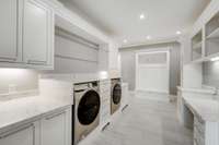 Built-in and elevated Samsung front load washer and dryer. A view of the drop zone and writing desk too.
