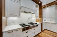 Custom running brick style glass and matte white tile backsplash with a wall-mount pot filler. Professional Viking 8-Burner cooktop with griddle option.