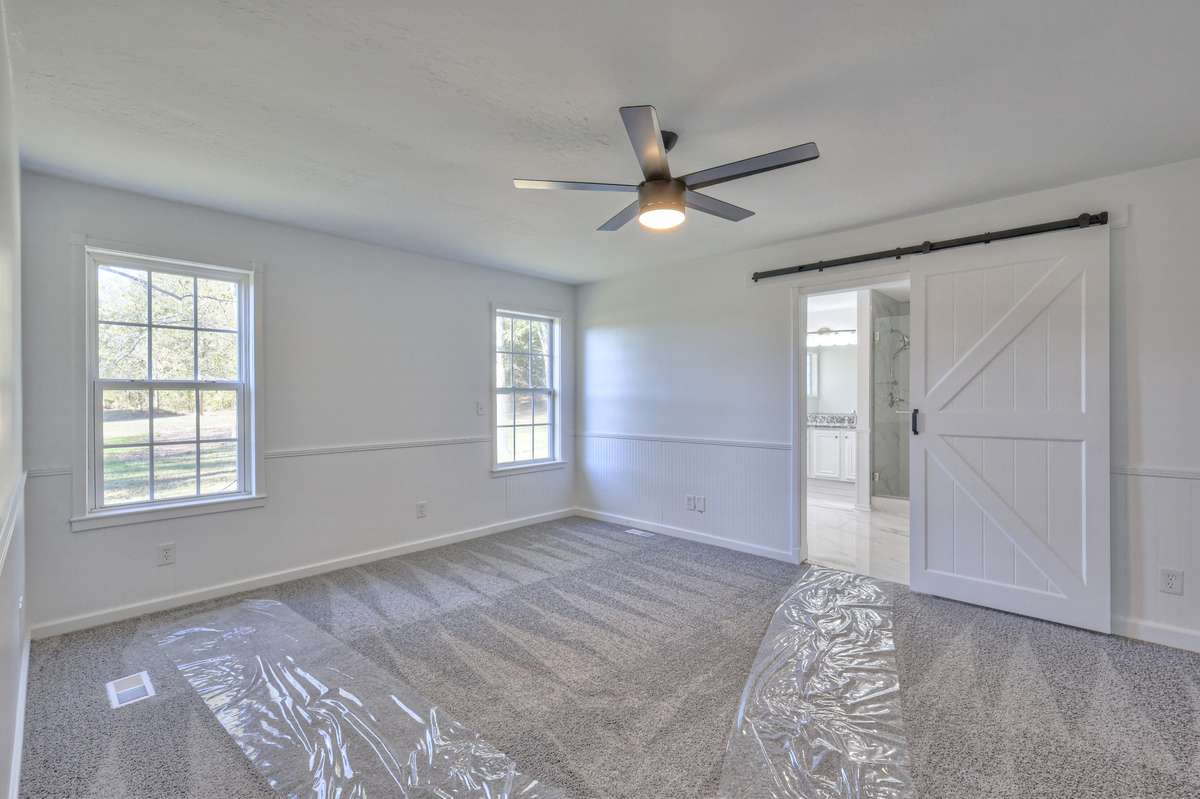 Master bedroom with plastic to protect new carpet.  Barn door entrance to bathroom