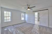 Master bedroom with plastic to protect new carpet.  Barn door entrance to bathroom