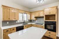 This farm style kitchen provides plenty of space on the stone countertops and lots of storage in the cabinetry.  Window overlooks backyard and beyond into the woods.
