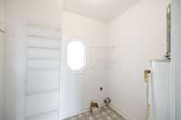 Spacious utility room with washer/dryer hookups and water heater and shelving.