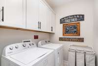 The laundry room has cabinetry and fixtures that make the space feel clean and organized.