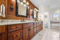 Primary bath w/ beautiful woodwork, double vanities & tile floors.