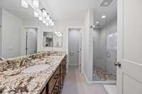 Primary en-suite with granite counter tops, double vanities, spacious shower, and incredible cabinets, and heated tile flooring.