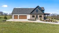 This modern farmhouse features a three-car garage, brick and board-and-batten exterior, and a spacious covered porch. Nestled on a scenic lot, it offers stunning views and a perfect blend of charm and functionality.