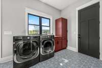 Style meets function! This spacious drop zone and laundry room features custom cabinetry, bold tile flooring, and abundant natural light. With built-in storage and a sink, it’s designed for convenience and organization.