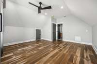 Spacious 4th bedroom with vaulted ceilings, modern fan, and brand-new California Closets. Features a private en-suite bath with herringbone tile, LED mirror, and sleek finishes for a stylish, functional retreat.