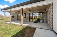 The back of the home features a spacious covered patio with scenic views, perfect for outdoor relaxation or entertaining. Its blend of brick and board-and-batten siding adds charm to this modern farmhouse design.