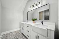 This elegant second-level bathroom features dual farmhouse sinks, a spacious vanity, and a beautifully tiled walk-in shower with a bench. The intricate tilework and modern fixtures add a touch of sophistication, making it both functional and stylish.