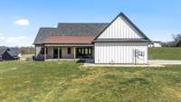 The back of the home features a spacious covered patio with scenic views, perfect for outdoor relaxation or entertaining. Its blend of brick and board-and-batten siding adds charm to this modern farmhouse design.