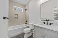 Secondary Bedroom En-suite - Full Bathroom – Elegant bath with tub/shower combo, custom tile, and marble-topped vanity.