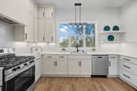 Bright kitchen with shaker cabinetry, stainless steel appliances, and quartz countertops with a overview of the backyard and river while preparing food for your guests.