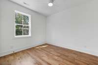 Secondary Bedroom – Bright bedroom with hardwood floors, ceiling fan, and double-door closet.