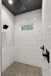 Custom tile design and transom window for natural light. Floor to ceiling tile, and tiled ceiling with task lights and built in niche for storage