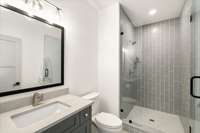 En suite bath with frameless shower and floor to ceiling tile