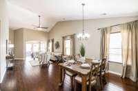 The open concept living and dining areas feature tall ceilings, extra windows for natural light, and hardwood flooring throughout the main living spaces.