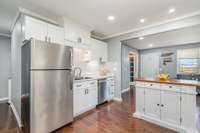 The kitchen boasts polished stainless steel appliances, elegant can lighting, upgraded fixtures, and an abundance of cabinet space for both style and functionality.
