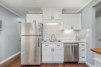 The kitchen is equipped with double stainless steel sinks adding to the modern design. Overhead cabinets provide additional storage in the kitchen, helping to maintain a clean and organized appearance.