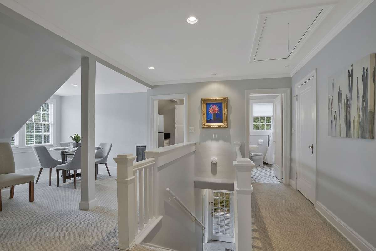 The second-level landing with views of the main level entry door off the side covered porch is shown with a dining table. All 3 levels of this home have multiple entrances.
