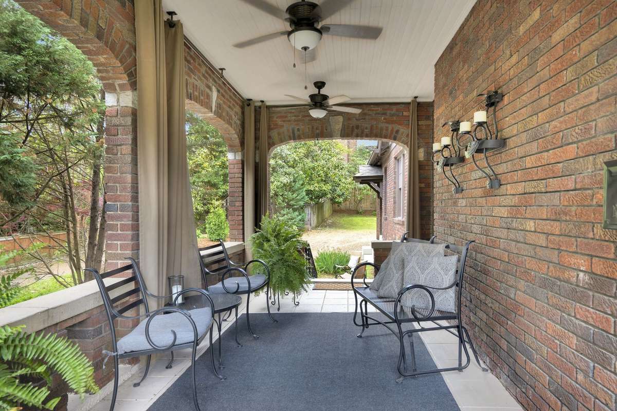 The covered side patio, with views of Elmington Park and the Middle School clock tower, features ceiling fans, lights, and sconces and can be enjoyed year-round.
