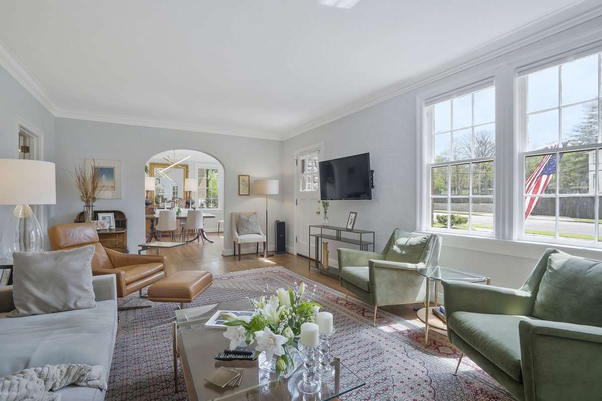 Formal living room with Crown Molding, Large windows, Stucco walls, Ventless Gas Fireplace, and original hardwoods.