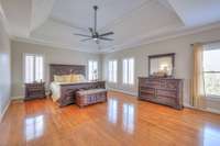 Primary Bedroom with gorgeous tray ceiling and glistening floors